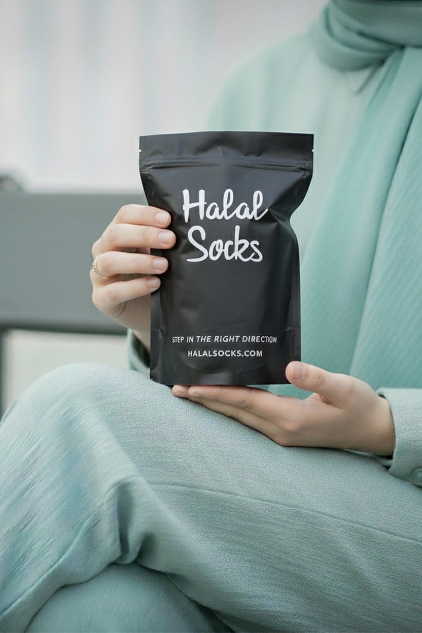 Person holding a black package labeled 'Halal Socks' with a blurred background